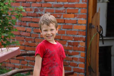 Tuğla ev önünde duran güzel bir çocuk gülüyor