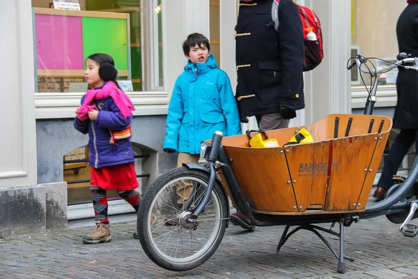 Menschen laufen an einem Fahrrad mit großem hölzernen Laderaum in der Mitte vorbei. — Stockfoto