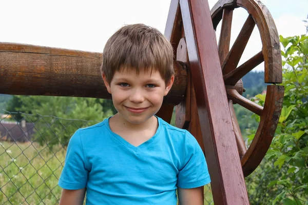 Smiling boy in front of old style wooden well — Stock Photo, Image