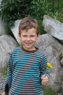 Karahindiba önünde büyük kayalar ile boy gülümseyerek