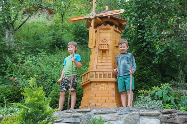 Two boys next to small mill in summer city park — Stock Photo, Image