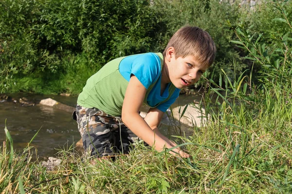 Улыбающийся мальчик у маленькой реки — стоковое фото