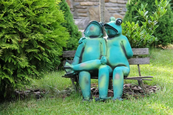 Decorative funny frogs sitting on bench in city park of Schodnic — Stock Photo, Image