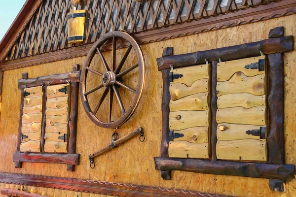 Casa de campo de madeira de estilo antigo com roda decorativa entre obturado — Fotografia de Stock