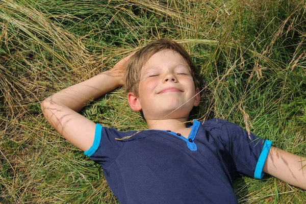 Knappe jongen liggen op gras van de weide — Stockfoto
