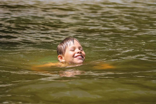 Улыбающийся мальчик плавает в озере Лицензионные Стоковые Фото