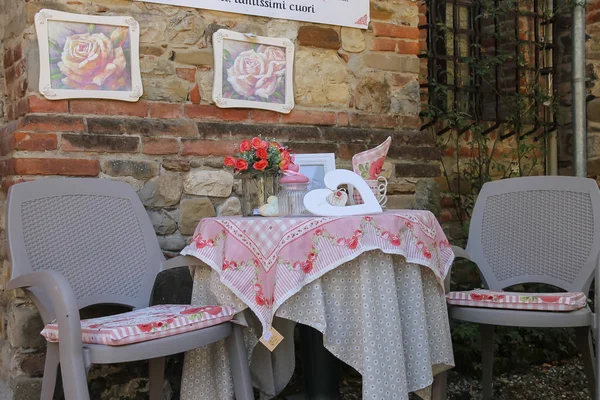 Dekorativní stolek s židlemi na pozadí kamenné zdi. Grazzano — Stock fotografie