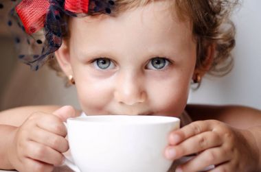 Kırmızı şapkalı küçük kız bir fincan çay içer