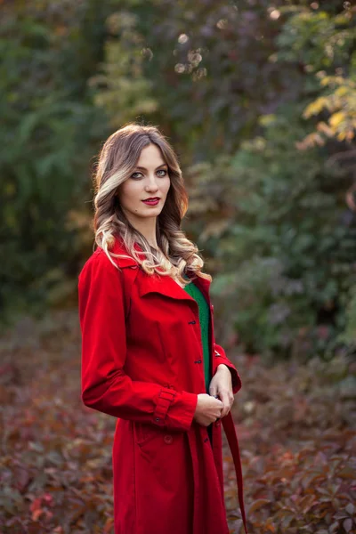 Meisje in een rode jas in de herfst — Stockfoto