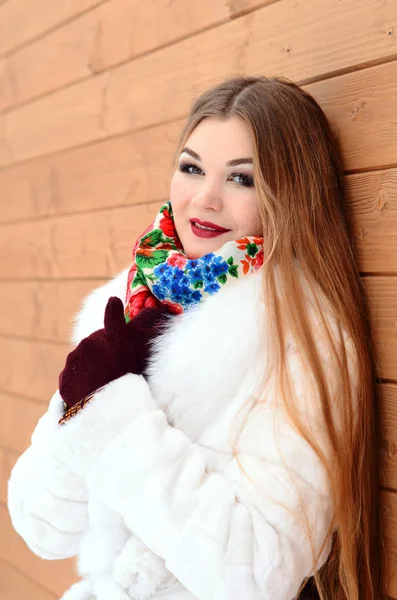 La chica con el pelo largo en invierno, ella en un abrigo de piel blanca. Fondo de madera —  Fotos de Stock