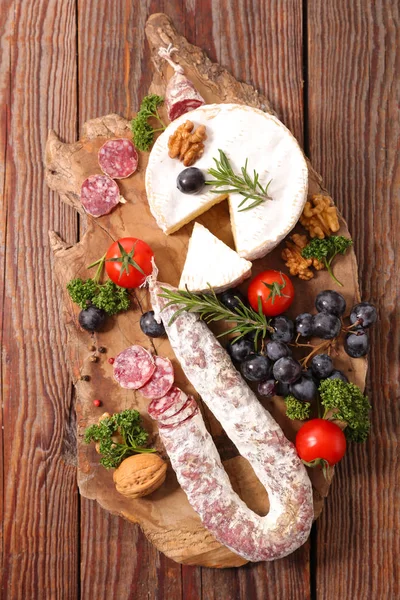Camembert und Snacks auf Holzbrett — Stockfoto