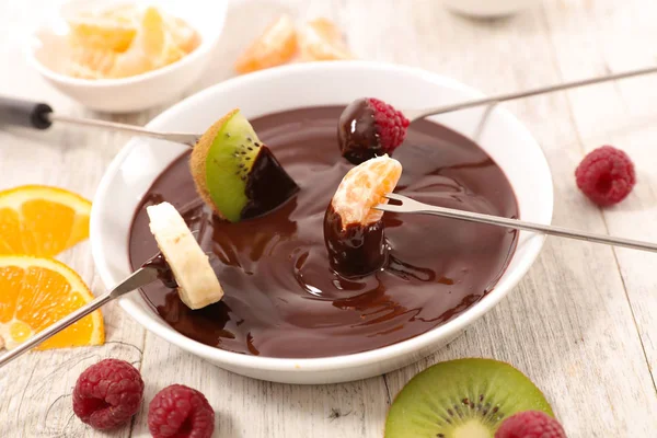 Fruits dipping in chocolate sauce — Stock Photo, Image