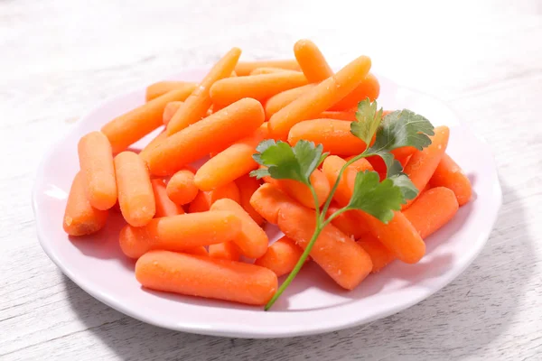 Little carrots on white plate — Stock Photo, Image
