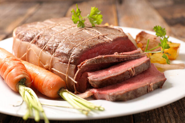 Roast beef and spices on wood background