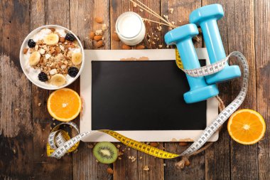 Granola, yoğurt, portakal ve kivi, metre ve mavi dumbbells ile kara tahta, üstten görünüm, sağlıklı gıda kavramı, kesmek