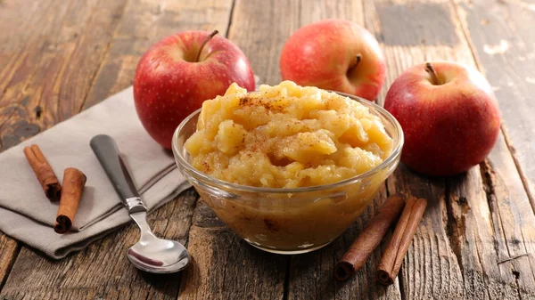 Apple sauce with cinnamon and fresh apples on raw wooden table
