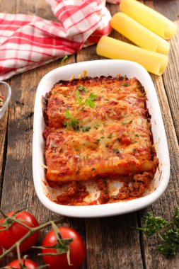 Sığır eti ve domates sos ile canneloni ahşap masa üzerinde görmek
