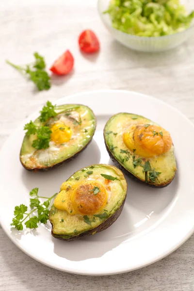 baked eggs in avocados on white plate