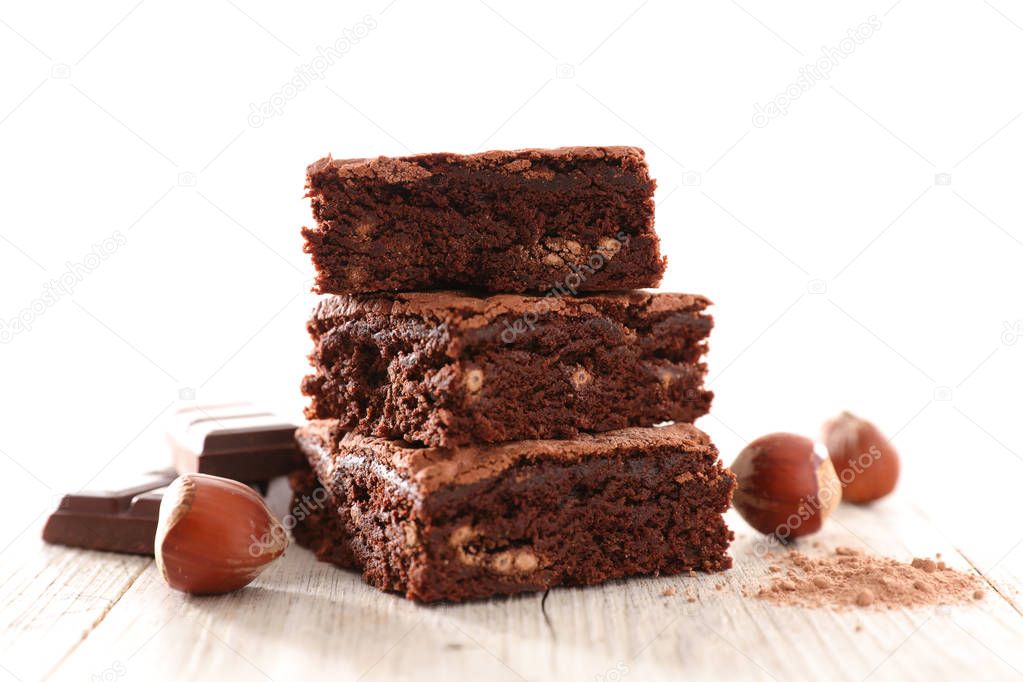 sliced chocolate brownie and hazelnuts on wooden table