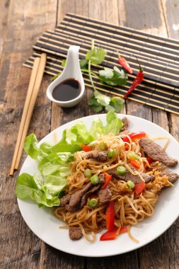 Fried stir fry erişte beyaz çubuklar, soya sosu ve kırmızı biber biber tabakta