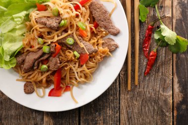 Fried stir fry erişte beyaz chopsticks ve kırmızı biber biber ile tabakta