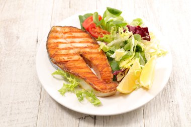 Izgara somon steak ve beyaz tabakta salata.