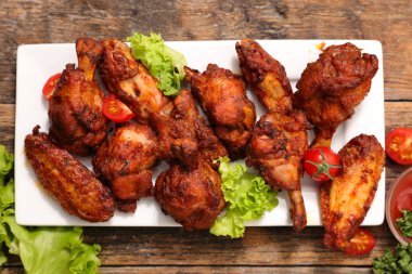 Kızarmış tavuk budu ve kanatlar üstten görünüm kiraz domates ve marul beyaz tabakta servis