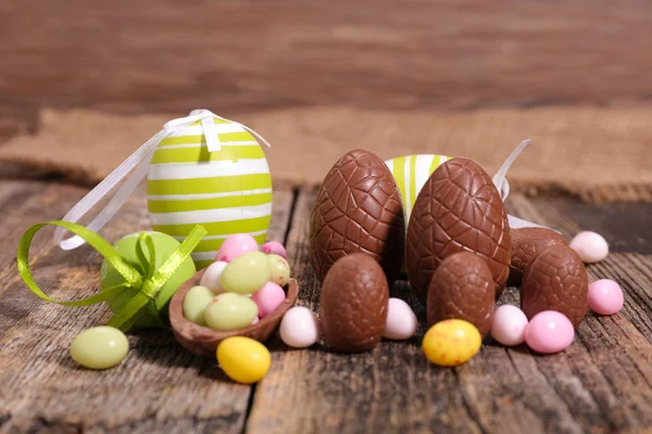 Easter chocolate eggs served on wooden table with glazed peanuts