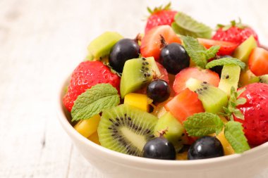 ahşap arka plan üzerinde tabak taze meyve salatası ile nane yaprakları