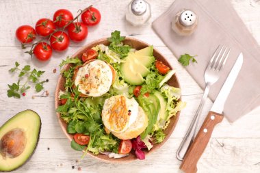 Yumurta Benedict ile taze yeşil salata dilimlenmiş avokado ve kiraz domates ile servis