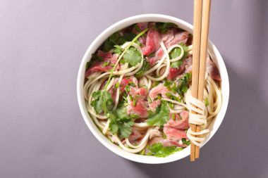 erişte ve et ve gri arka plan üzerinde ahşap yemek çubukları ile Çin çorbası