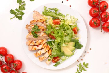 kızarmış tavuk beyaz plaka üzerinde yeşil salata ile servis dilimlenmiş