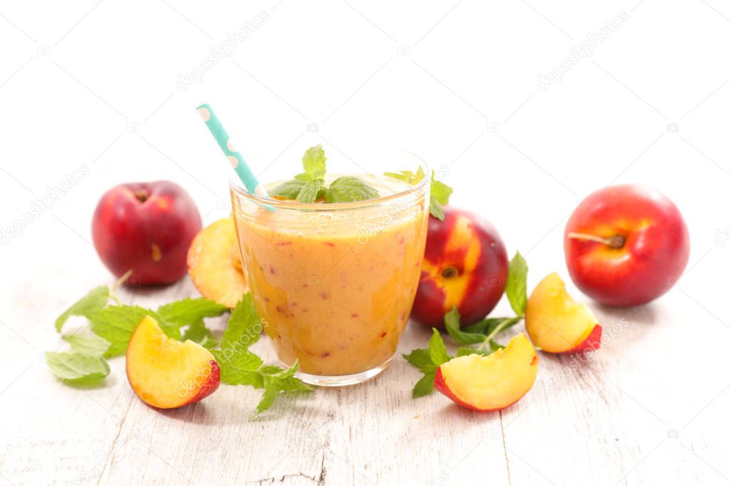 fresh smoothie with peaches and mint leaves on light wooden table