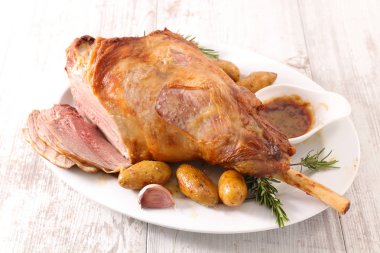 Beyaz tabakta kuzu bacak patates ve sos ile