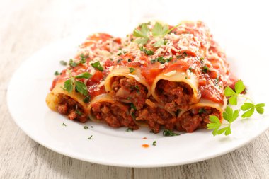 Beyaz tabak içinde sığır eti ve domates soslu Canneloni