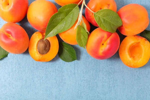 Verse Rijpe Abrikozen Met Bladeren Blauwe Achtergrond — Stockfoto