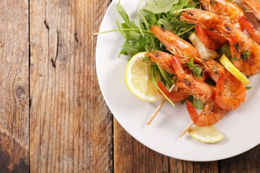 Ahşap arka planda kızarmış karides şişi.