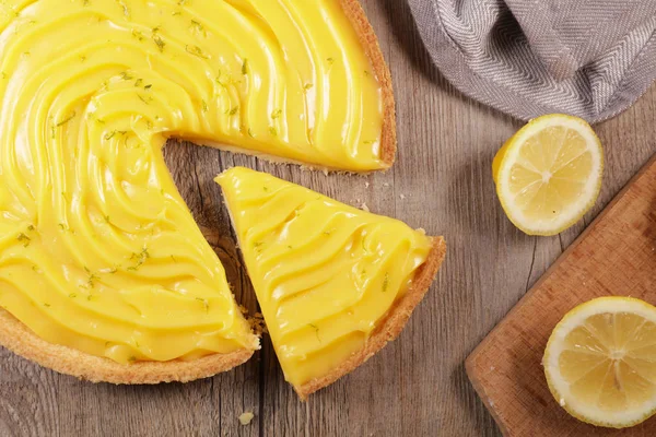 lemon pie and slice on wood background