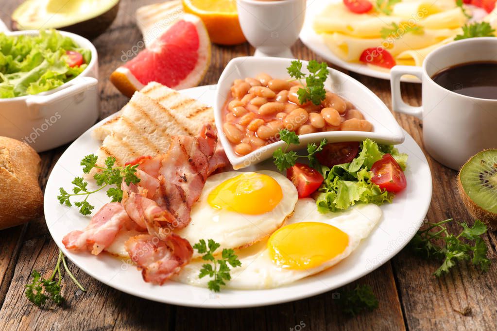 english full breakfast with fried egg, bacon,cheese, toast, coffee and fruits