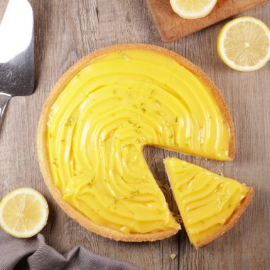 Tahta arka planda dilimlenmiş limon turtası