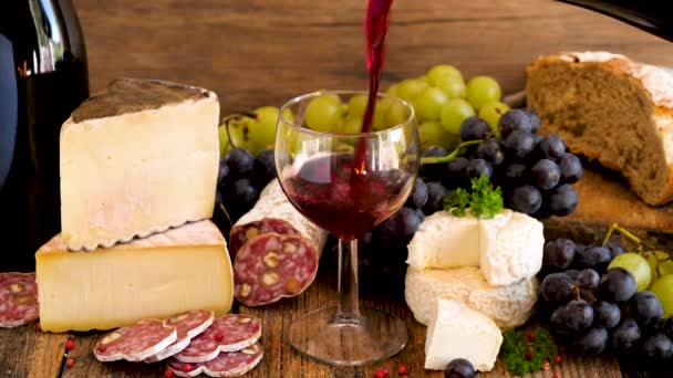 チーズ ブドウ サラミ パンを入れたグラスに赤ワインを注ぐ — ストック動画