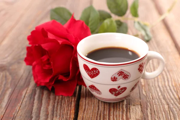 coffee cup and red rose on wood background