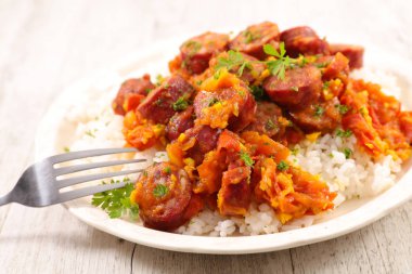 Pirinçli tabak ve domates soslu baharatlı sosis.