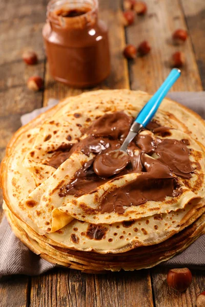 crepe with chocolate spread and hazelnut on wood background