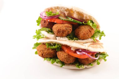 Beyaz arka planda izole edilmiş falafel, sebze ve sosla dolu pita ekmeği.