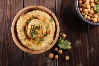 Tahta arka planda bir kase humus.