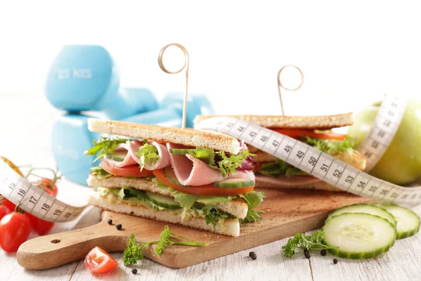 club sandwich, dumbbell and meter tape- diet food concept