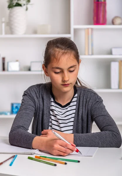 Mooi meisje op haar schoolproject thuis werken. — Stockfoto