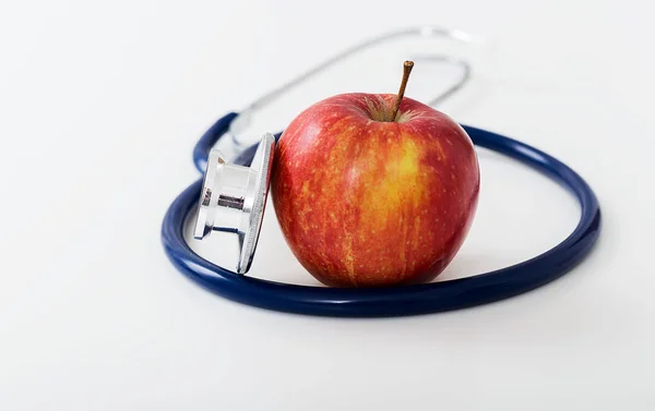 Rött äpple och stetoskop på vit bakgrund. — Stockfoto
