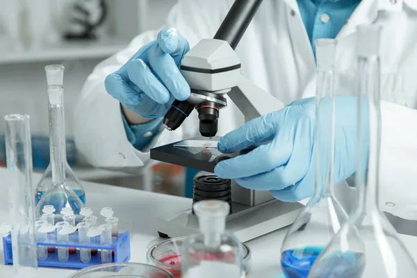 Men in a laboratory microscope with microscope slide in hand — Stock Photo, Image